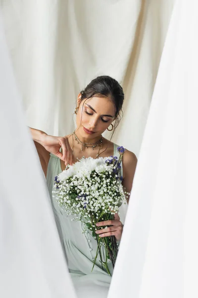 Brunette woman looking at bouquet of flowers on white — Stock Photo