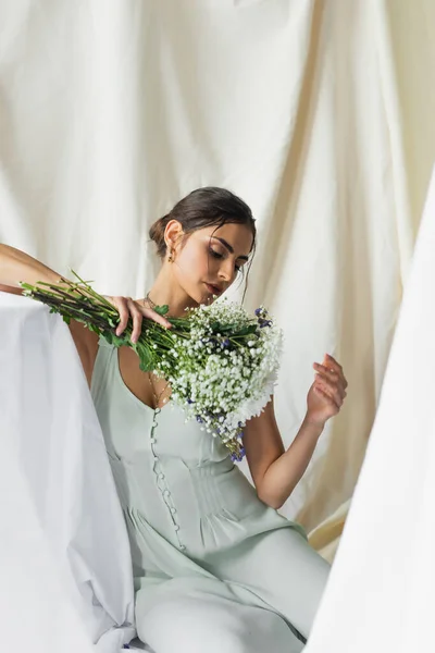 Jolie femme regardant bouquet de fleurs sur blanc — Photo de stock