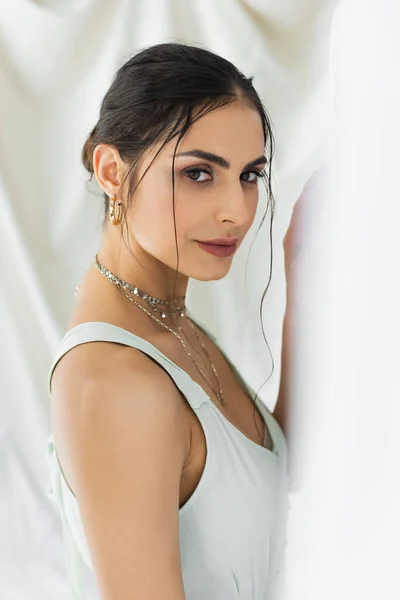 Brunette woman in dress looking at camera while posing on white — Stock Photo