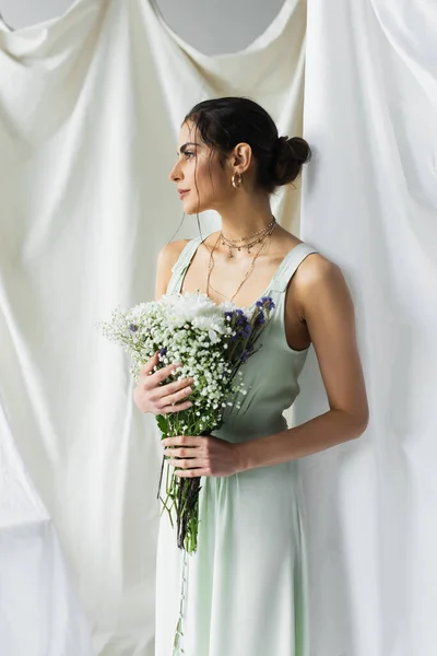 Brünette Frau im Kleid mit Blumenstrauß auf weißem Grund — Stockfoto