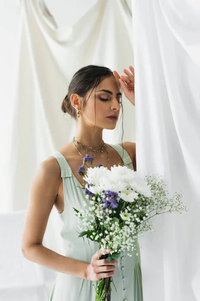 Donna bruna in posa vestito con mazzo di fiori su bianco — Foto stock