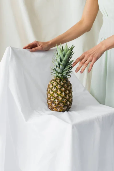 Abgeschnittene Ansicht eines Modells, das nahe der reifen Ananas auf Weiß posiert — Stockfoto