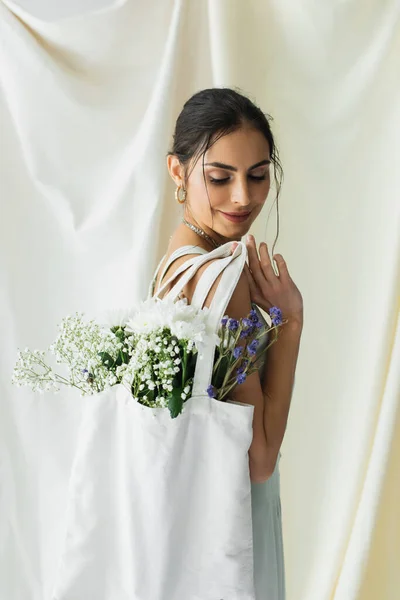 Gioiosa donna che tiene borsa shopper tessuto con fiori su bianco — Foto stock