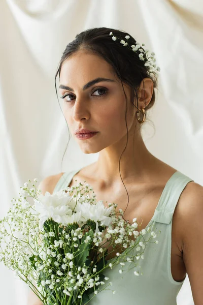 Brunette woman near bouquet of blooming flowers on white — Stock Photo