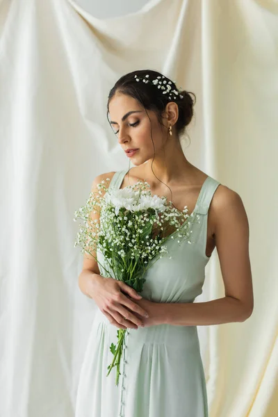 Brunette woman holding bouquet of blooming flowers on white — Stock Photo