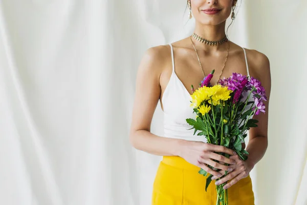 Vista recortada de la mujer feliz en la parte superior de la cosecha con flores en blanco - foto de stock