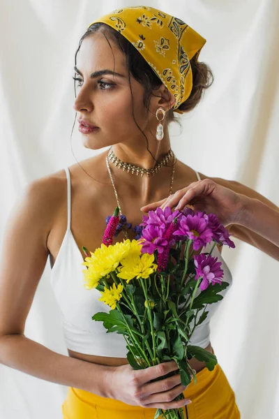 Woman in yellow headscarf holding bouquet of flowers on white — Stock Photo