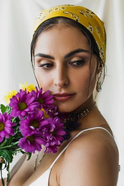 Mulher bonita em lenço de cabeça segurando flores no branco — Fotografia de Stock