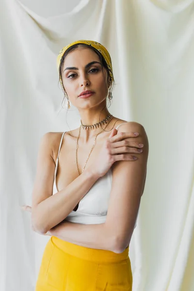 Mujer en pañuelo amarillo y top de la cosecha posando en blanco - foto de stock