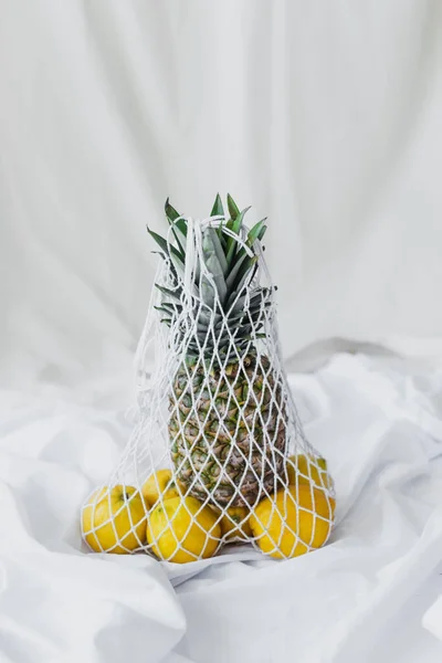 Reusable string bag with lemons and pineapple on white — Stock Photo