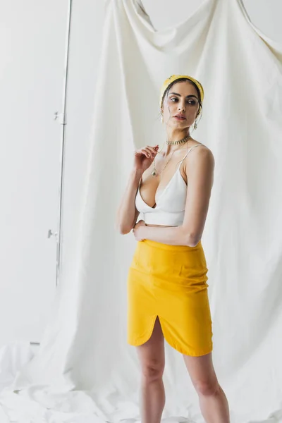 Brunette woman in yellow skirt and crop top posing on white — Stock Photo