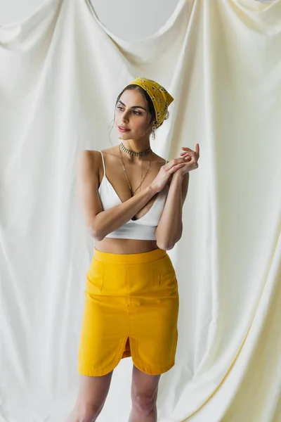 Elegante donna in velo giallo, gonna e crop top in posa su bianco — Foto stock