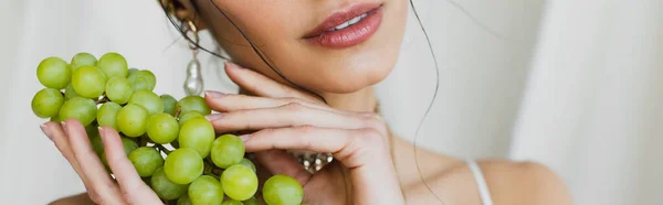 Vue recadrée de la femme tenant des raisins sur blanc, bannière — Photo de stock