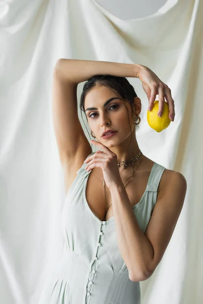 Mulher bonita no vestido posando com limão fresco no branco — Fotografia de Stock