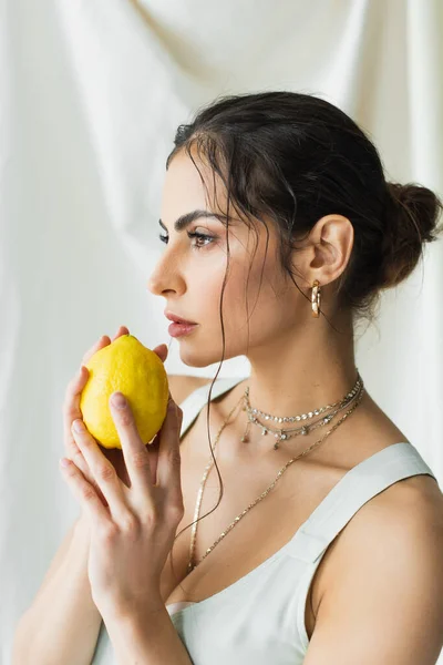Bella donna in abito che tiene limone fresco su bianco — Foto stock