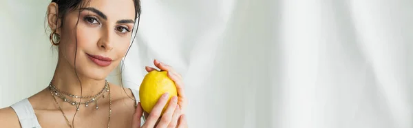 Усміхнена жінка тримає свіжий лимон на білому, банер — стокове фото