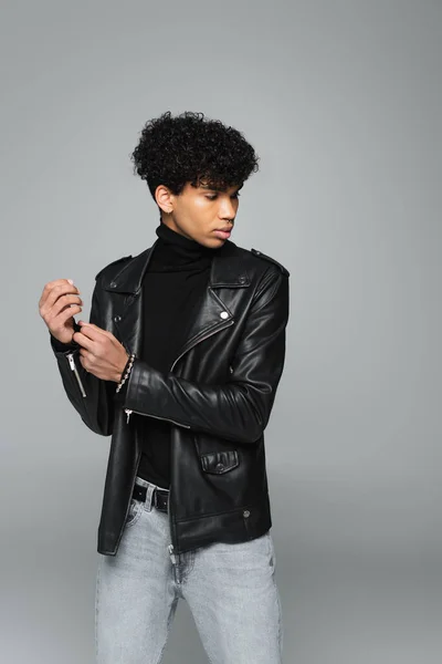 African american man in trendy leather jacket posing isolated on grey — Foto stock