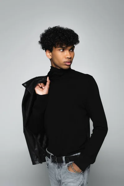 Stylish african american man looking away while standing with hand in pocket of jeans isolated on grey — Stock Photo