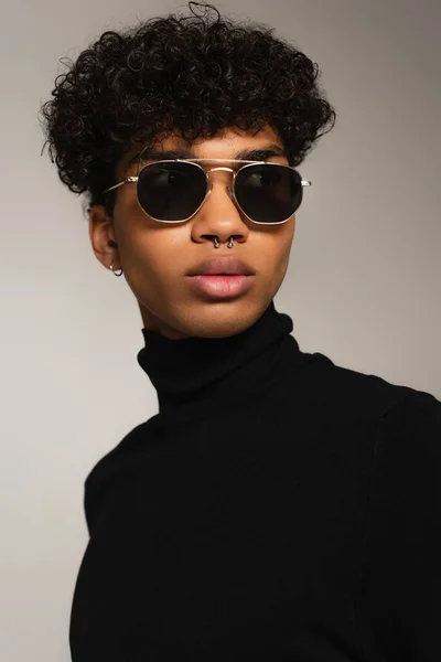 Portrait of pierced african american man in dark sunglasses and black turtleneck isolated on grey — Photo de stock