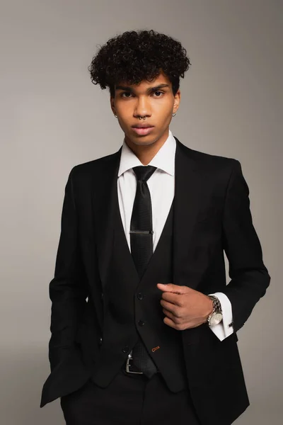 Молодий афроамериканський чоловік у чорному трилистовому костюмі тримає руку в кишені ізольовано на сірому — стокове фото
