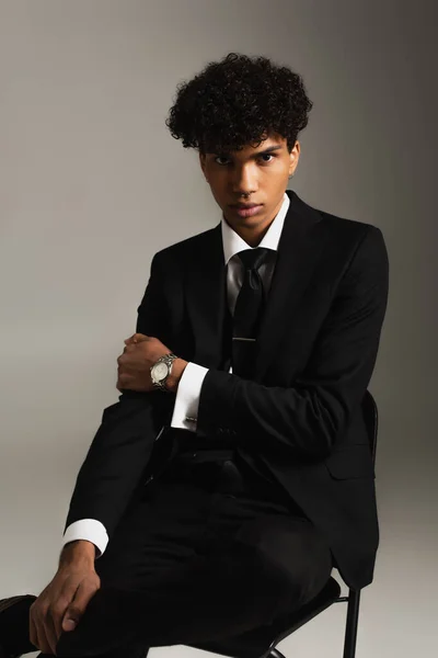 African american man in black elegant suit looking at camera on grey background — Foto stock