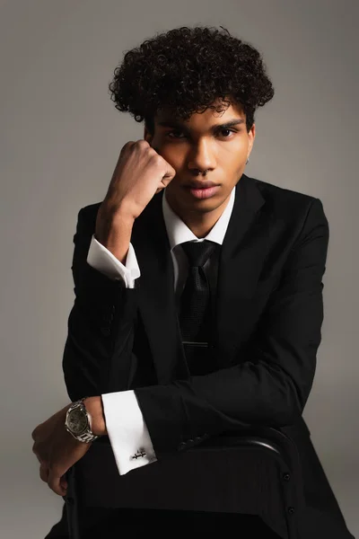 African american businessman in elegant formal wear looking at camera while posing on grey — Stock Photo