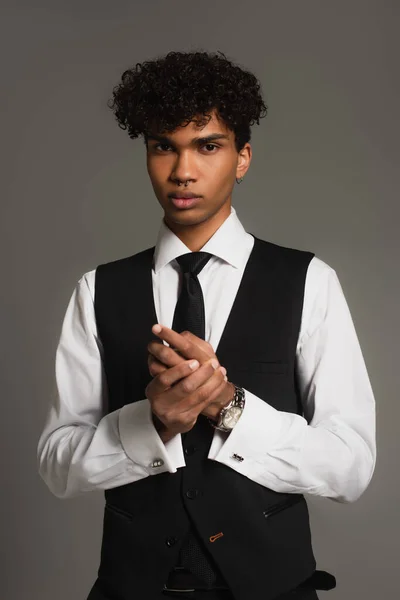 Young african american man in white shirt and black vest looking at camera isolated on grey - foto de stock