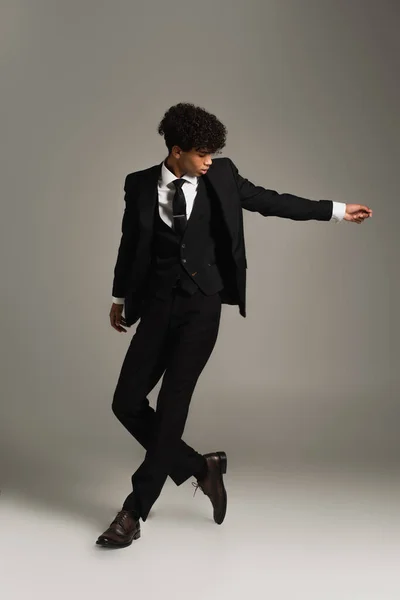 Full length view of african american man posing in elegant three-piece suit and oxford shoes on grey - foto de stock