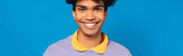 Pleased african american man with piercing looking at camera isolated on blue, banner — Foto stock