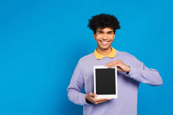 Fröhlicher afrikanisch-amerikanischer Mann zeigt digitales Tablet mit leerem Bildschirm isoliert auf blau — Stockfoto