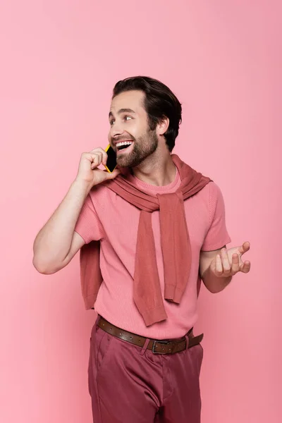 Hombre positivo en camiseta hablando en smartphone aislado en rosa - foto de stock