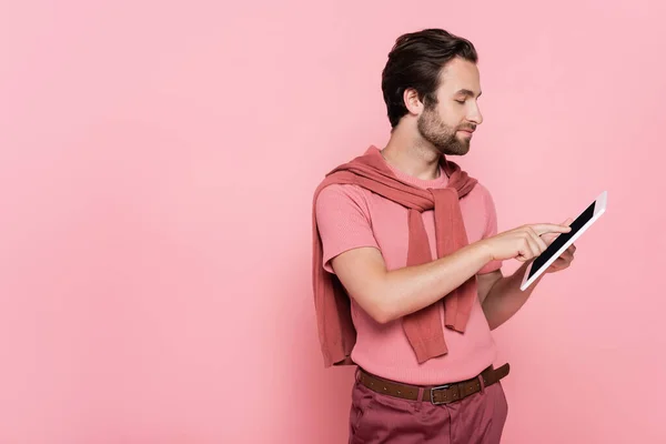 Vista lateral do homem com jumper nos ombros usando tablet digital isolado em rosa — Fotografia de Stock