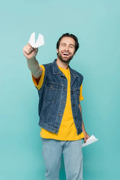 Uomo sorridente che tiene aerei di carta isolati su blu — Foto stock