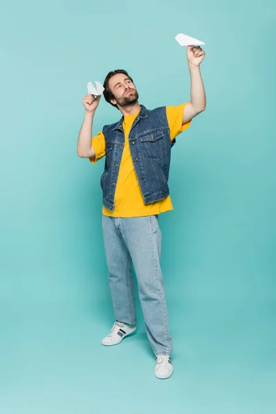 Comprimento total do homem jogando com aviões de papel em fundo azul — Fotografia de Stock