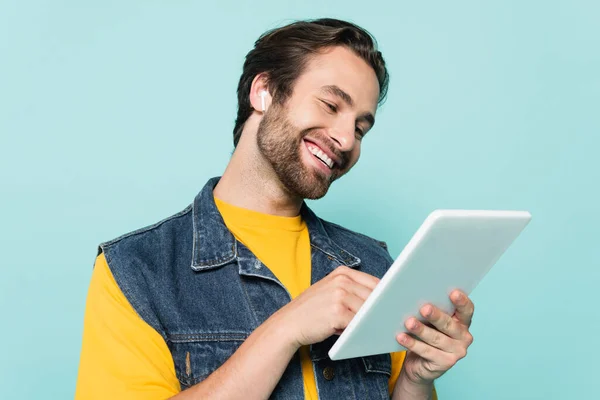 Hombre joven en auriculares usando tableta digital aislada en azul - foto de stock