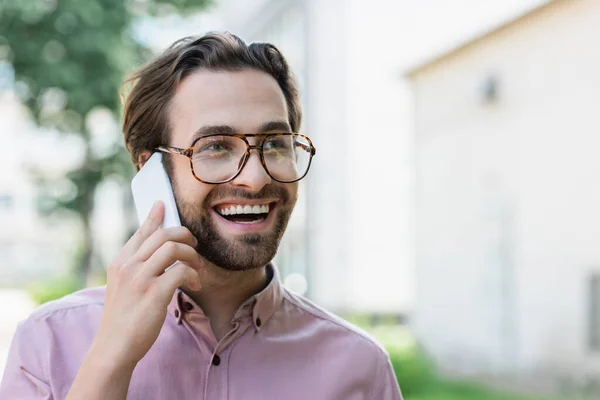 Hombre de negocios alegre hablando en el teléfono móvil al aire libre - foto de stock