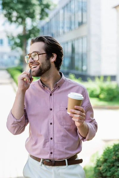 Empresário sorridente com café para ir falar no celular — Fotografia de Stock