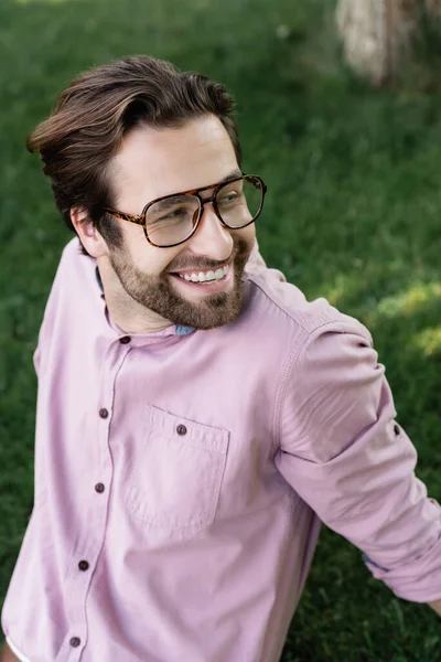 Homme d'affaires souriant à lunettes regardant loin dans le parc — Photo de stock