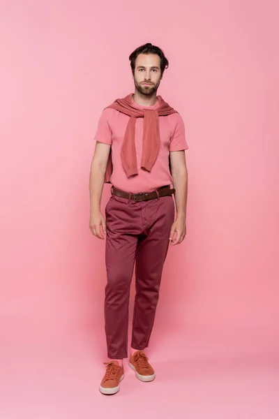 Full length of young man looking at camera on pink background — Stock Photo