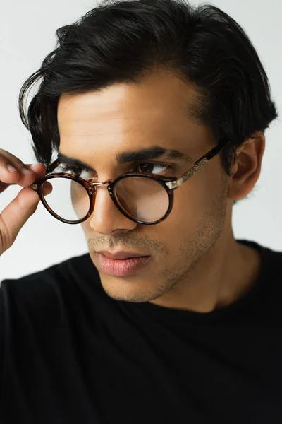 Stylish man adjusting eyeglasses isolated on grey — Stock Photo