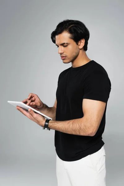 Jeune homme en t-shirt noir avec tablette numérique isolée sur gris — Photo de stock