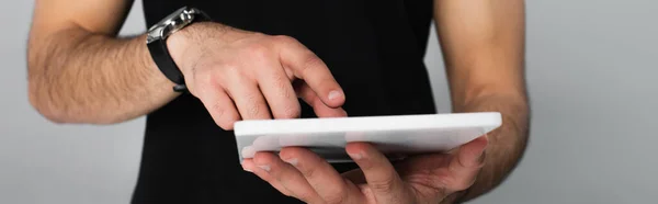 Vue partielle du jeune homme en t-shirt noir pointant vers la tablette numérique isolée sur gris — Photo de stock