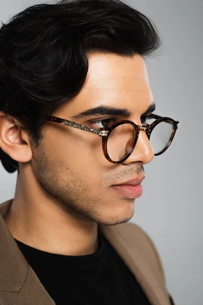 Ritratto di giovane uomo in occhiali alla moda posa isolato su grigio — Foto stock