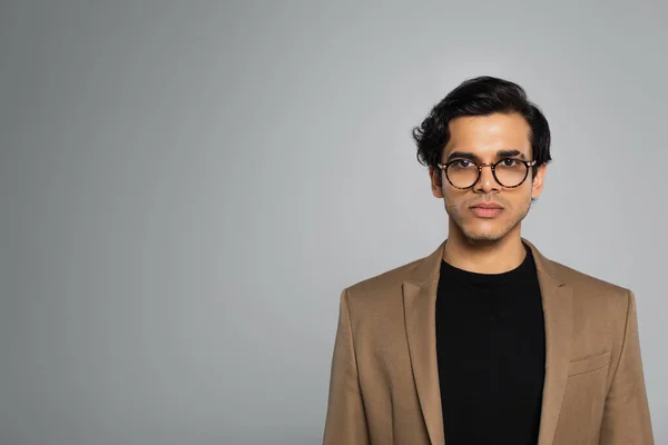 Junger Mann mit stylischer Brille blickt isoliert auf graue Kamera — Stockfoto