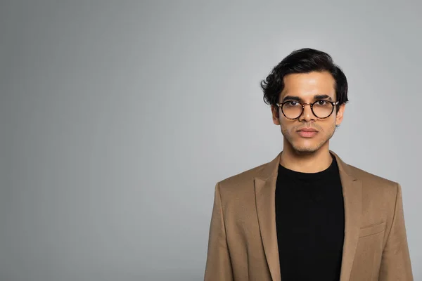 Jeune homme aux lunettes élégantes regardant la caméra isolée sur gris — Photo de stock