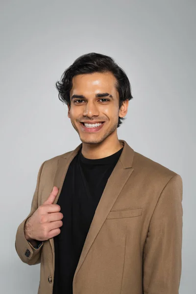 Cheerful young man in stylish blazer posing isolated on grey — Stock Photo