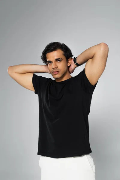 Jovem elegante homem em preto t-shirt posando isolado no cinza — Fotografia de Stock