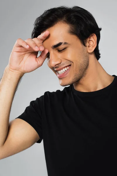 Jeune homme joyeux en t-shirt noir posant isolé sur gris — Photo de stock