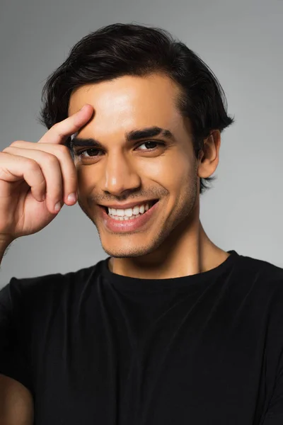 Jovem alegre homem em preto t-shirt posando isolado no cinza — Fotografia de Stock