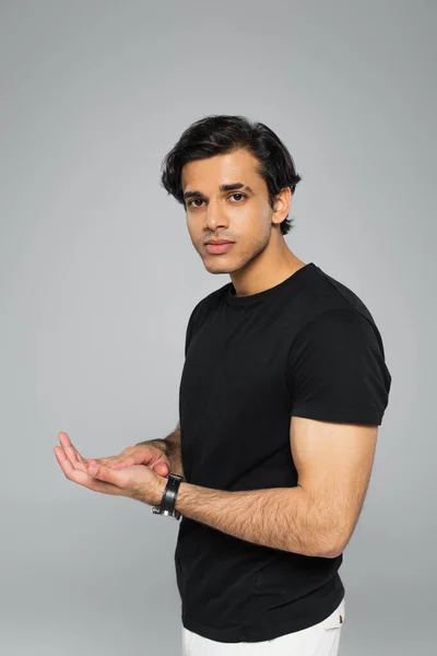 Young man in t-shirt looking at camera while posing isolated on grey — Stock Photo